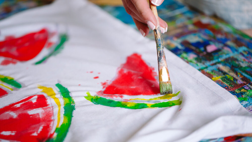 mulher pintando pedaços de melancia em uma pano branco